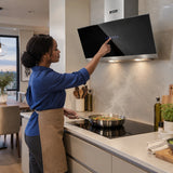 African American home cook adjusts the Kaiser black glass hood while preparing food on the hob