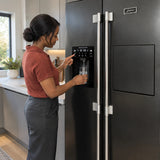 African American adult filling a glass from the front dispenser of a Kaiser black stainless steel refrigerator