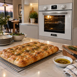Freshly baked focaccia cooling beside the Kaiser white and black multifunction electric oven in a contemporary kitchen