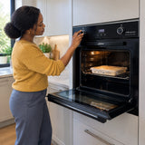 African American home cook selecting the cold-air defrost setting on a Kaiser black built-in electric oven