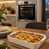 Finished browned vegetable gratin ready to serve with the Kaiser EH 6323 stainless steel oven visible in the adjoining kitchen.