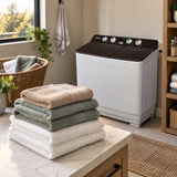 Folded clean towels ready beside a closed Decakila 15kg twin-tub washing machine in an organised home laundry room.