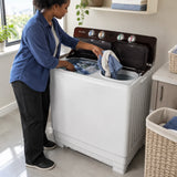 African American adult transferring damp towels from the wash tub to the separate spin tub of a Decakila twin-tub washing machine.