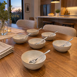 Six matching Decakila stainless steel spoons remain beside finished dessert bowls after a shared meal.