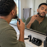 African American adult using the Decakila cordless detail trimmer to refine a beard edge at a contemporary bathroom mirror.