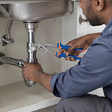 African American maintenance technician using Wadfow pump pliers to turn a plumbing fitting beneath a utility-room sink.