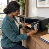 African American adult storing household documents in an open Wadfow WEB1535 electronic safe in a home office