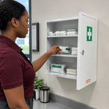 Facilities coordinator retrieves a first-aid dressing pack from an open Wadfow three-compartment wall cabinet