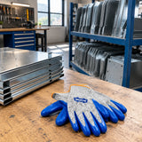 Organised sheet-metal components with Wadfow cut-resistant gloves resting nearby in a clean fabrication staging area.