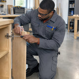 African American cabinet repair technician wearing a grey Wadfow WUN2802.L coverall while securing a cabinet hinge