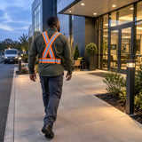 Worker wearing a Wadfow fluorescent orange reflective vest walking along a commercial service route at dusk