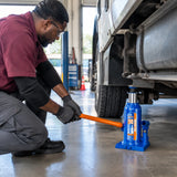 African American technician pumps a Wadfow WHJ1510 bottle jack beneath a compatible commercial vehicle in a clean service bay