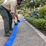 African American groundskeeper laying a Wadfow blue lay-flat hose along a landscaped planting bed