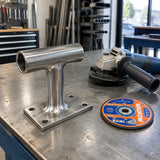 Finished steel handrail bracket with a blended weld beside the inactive Wadfow WAC1347 grinding disc and angle grinder