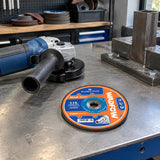 Unused Wadfow WAC1347 grinding disc resting beside a compatible angle grinder on an organised metalworking bench