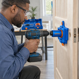 African American door installer using the Wadfow WKJ2404 plastic guide and 54mm hole saw to prepare a lock opening in a supported door