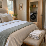 Freshly laundered guest-room bed linen with the Luxell front-load washing machine visible in the adjoining laundry cupboard.
