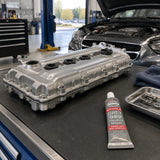 Reassembled engine cover and ABRO Grey 999 gasket maker in a clean automotive workshop after a sealing repair