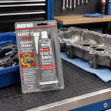 Sealed ABRO Grey 999 gasket maker resting beside an engine component on an organised automotive workshop bench
