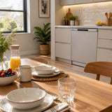 Clean plates and glasses ready for breakfast beside a closed Luxell integrated dishwasher in a tidy contemporary kitchen