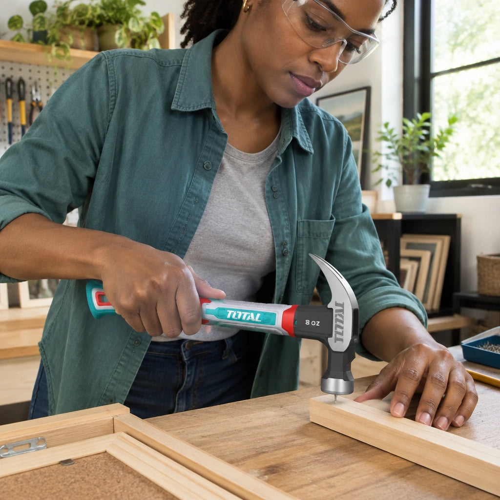 African American homeowner using the Total THCH61008 claw hammer to secure a small wooden frame component