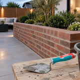 Completed brick garden wall with the Total THT82816 trowel resting nearby in a finished courtyard