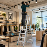 African American facilities technician adjusts a high retail track light from an open Total THLAD01071 double-sided ladder.