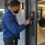 African American facilities coordinator communicates with an off-frame visitor through the C31-6085 smart lock at a shared studio entrance.