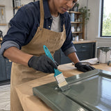 African American furniture refinisher using a Total 1-inch oil paint brush to coat a wooden cabinet door