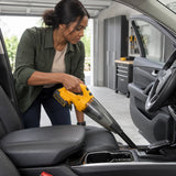 African American homeowner using the Ingco CVLI20126 cordless vacuum with crevice nozzle to clean debris beside a car centre console.