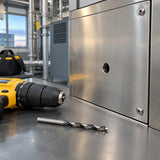 Finished stainless-steel service panel with a clean 14 mm hole and Ingco drill bit nearby