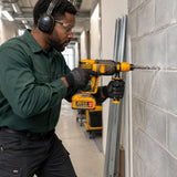 Technician using the Ingco CRHLI202689 cordless SDS Plus rotary hammer to drill a concrete block wall.