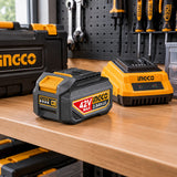 Ingco 42V 2.5Ah lithium-ion battery resting on an organised cordless-tool workshop shelf beside a compatible charger.