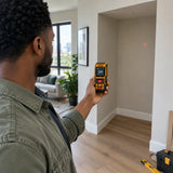 African American interior installer using an Ingco HLDD10089 laser distance detector to measure a living room alcove
