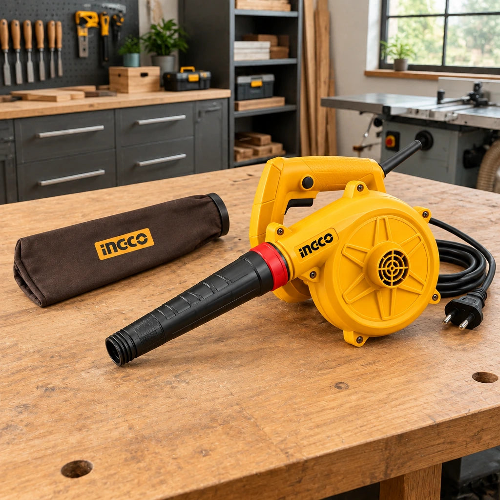 Ingco AB4068 electric blower resting on a cabinetmaking workshop bench with its supplied dust bag nearby.