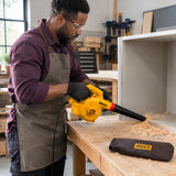 African American cabinetmaker using the Ingco AB4068 electric blower to clear wood shavings from a cabinet component in a workshop.