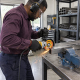 African American metal-fabrication technician using an Ingco 115mm cutting disc on a secured stainless-steel tube in a workshop.