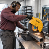 Metal-fabrication technician using an Ingco 355mm cutting disc to cut clamped stainless-steel square tube in a workshop
