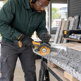 African American stone installer cutting a supported granite sill with an Ingco 115mm flanged diamond disc on a cordless angle grinder