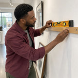African American gallery installer using an Ingco 40cm spirit level to align a wall display rail