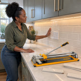 Completed ceramic kitchen backsplash with an Ingco manual tile cutter resting nearby