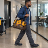African American facilities technician carrying an Ingco HTBG12 tool bag by its shoulder strap through a commercial corridor