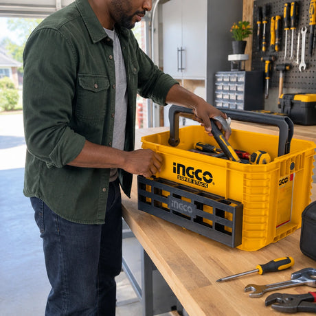 African American homeowner organizing hand tools inside an Ingco PBXS104 yellow stackable tote in a garage workshop.