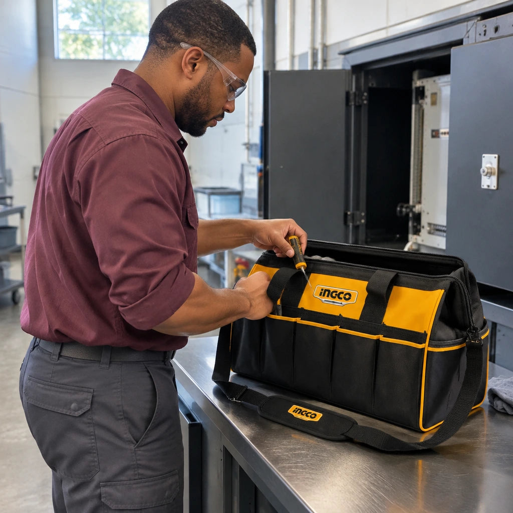 African American maintenance worker retrieving a hand tool from an open Ingco HTBG282228 tool bag beside a service cabinet