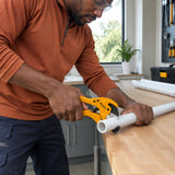 African American plumbing installer using the Ingco HPC3142 to cut compatible plastic pipe in a utility room