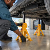 African American home mechanic positioning an Ingco HJS0201 jack stand beneath a raised vehicle in a clean garage.