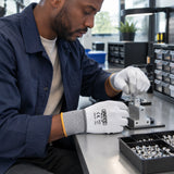 Technician wearing Ingco HGPUG62 gloves placing a small fastener in a precision assembly fixture