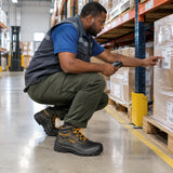 African American warehouse operator wearing Ingco SSH04SB.47 steel-toe safety boots while checking inventory beside an organised pallet lane.