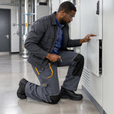 African American maintenance fitter wearing Ingco WUCT8022.L work trousers while kneeling to secure a commercial utility cabinet panel