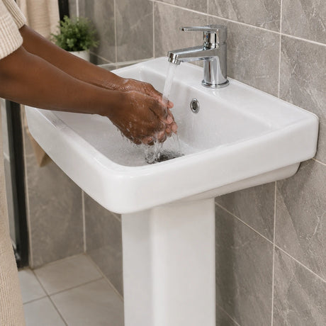 Hands washing under running water in a Nate BR Fabia white ceramic pedestal basin